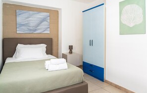 Ein ordentlich bezogenes Bett mit weißen Leinen, einem Kopfteil und einem an der Wand befestigten abstrakten Kunstwerk.