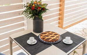 Ein Tisch mit einem Kuchen auf einem Teller, zwei Tassen und einer Blumenvase.