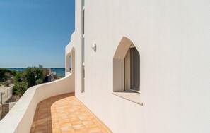 Ein gebogener Balkon mit Fliesenboden, einer weißen Wand und einem Fenster mit Meerblick.