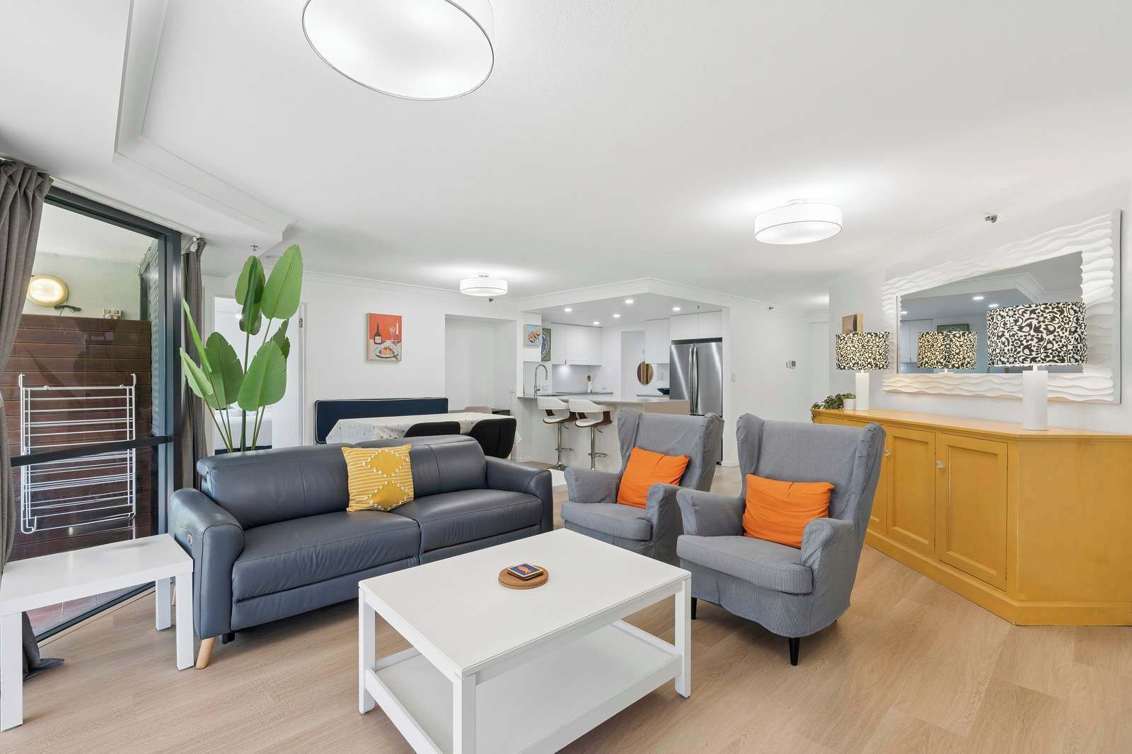 A modern living room with a sofa, armchairs, a coffee table, and a dining area.