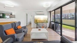Een moderne woonkamer met een bank, salontafel en uitzicht door grote ramen.