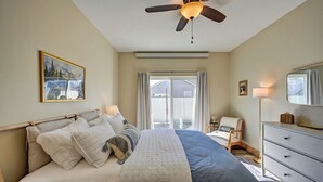 Quarto com cama, ventoinha no teto, janela com cortinas, cômoda e um quadro na parede.