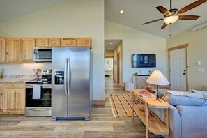 A modern kitchen with wooden cabinets, stainless steel appliances, and a dining area with a sofa and table. - Cloud Cottage | Parkside • Pet Friendly • STR 334 (Buena Vista)
