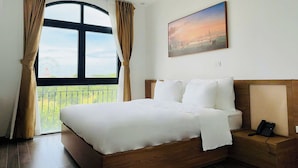 Une chambre d’hôtel avec un grand lit, un tableau, un téléphone et une vue sur une grande roue, visible par la fenêtre.