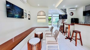 Un intérieur moderne avec un bar, des sièges et un téléviseur fixé au mur.