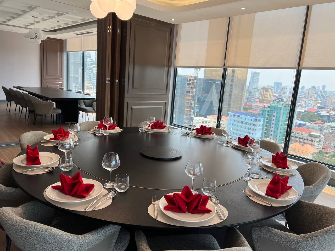 A conference room with a round table, chairs, and a city view.
