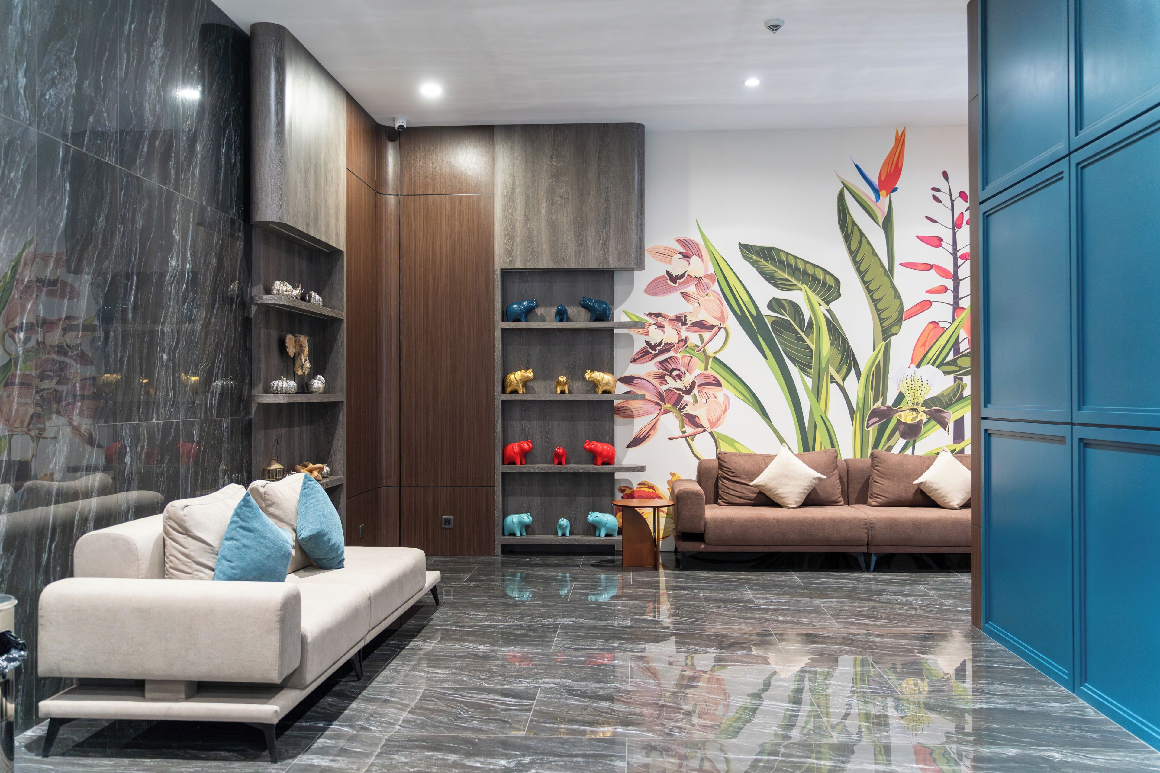 A modern living room with a sofa, a coffee table, and a wall with a floral mural.
