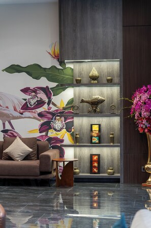 Een moderne woonkamer met een bank, een salontafel en een decoratieve muur met een bloemenmuur.
