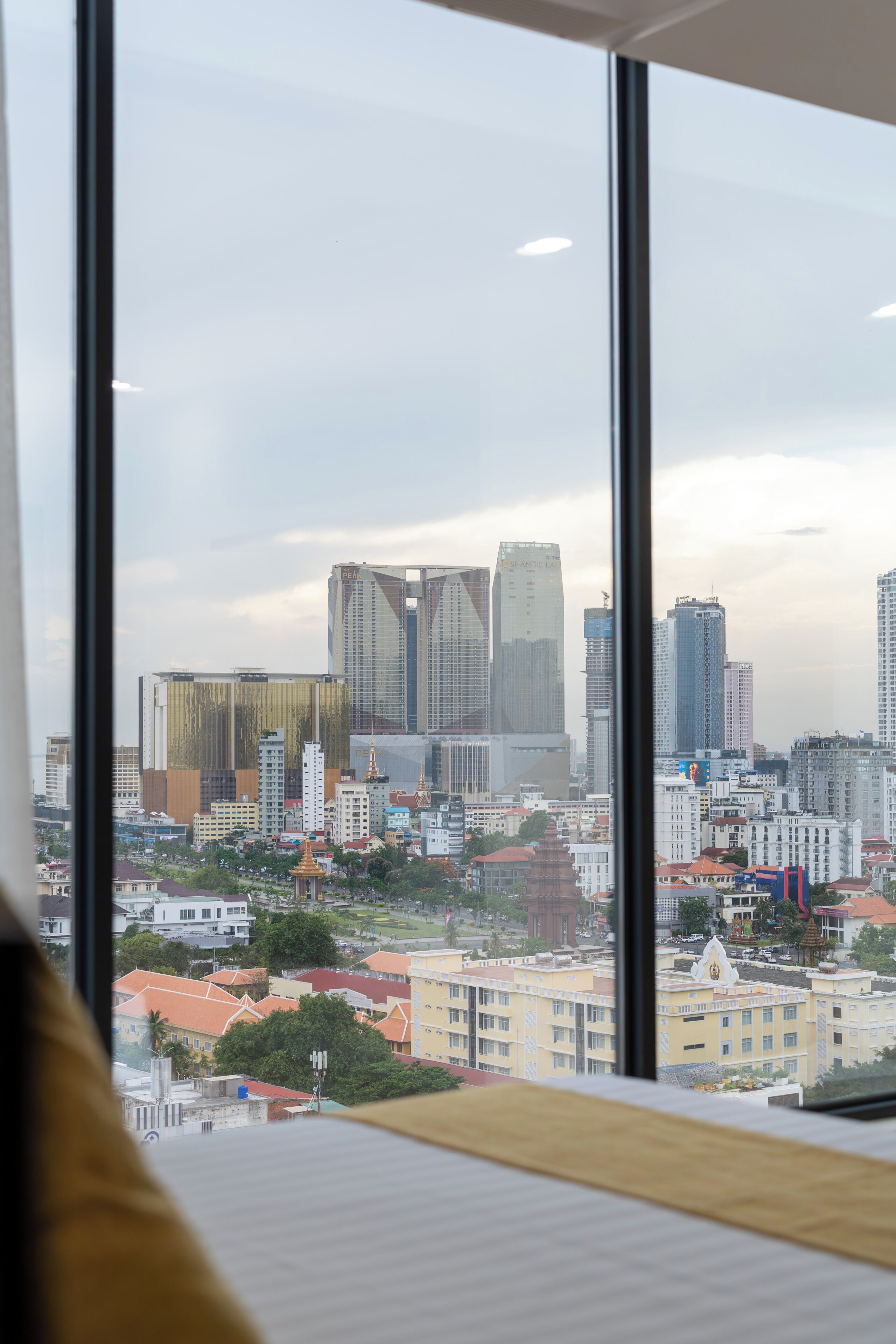 A cityscape through large windows with modern buildings, including a prominent skyscraper labeled 'PEAK.'