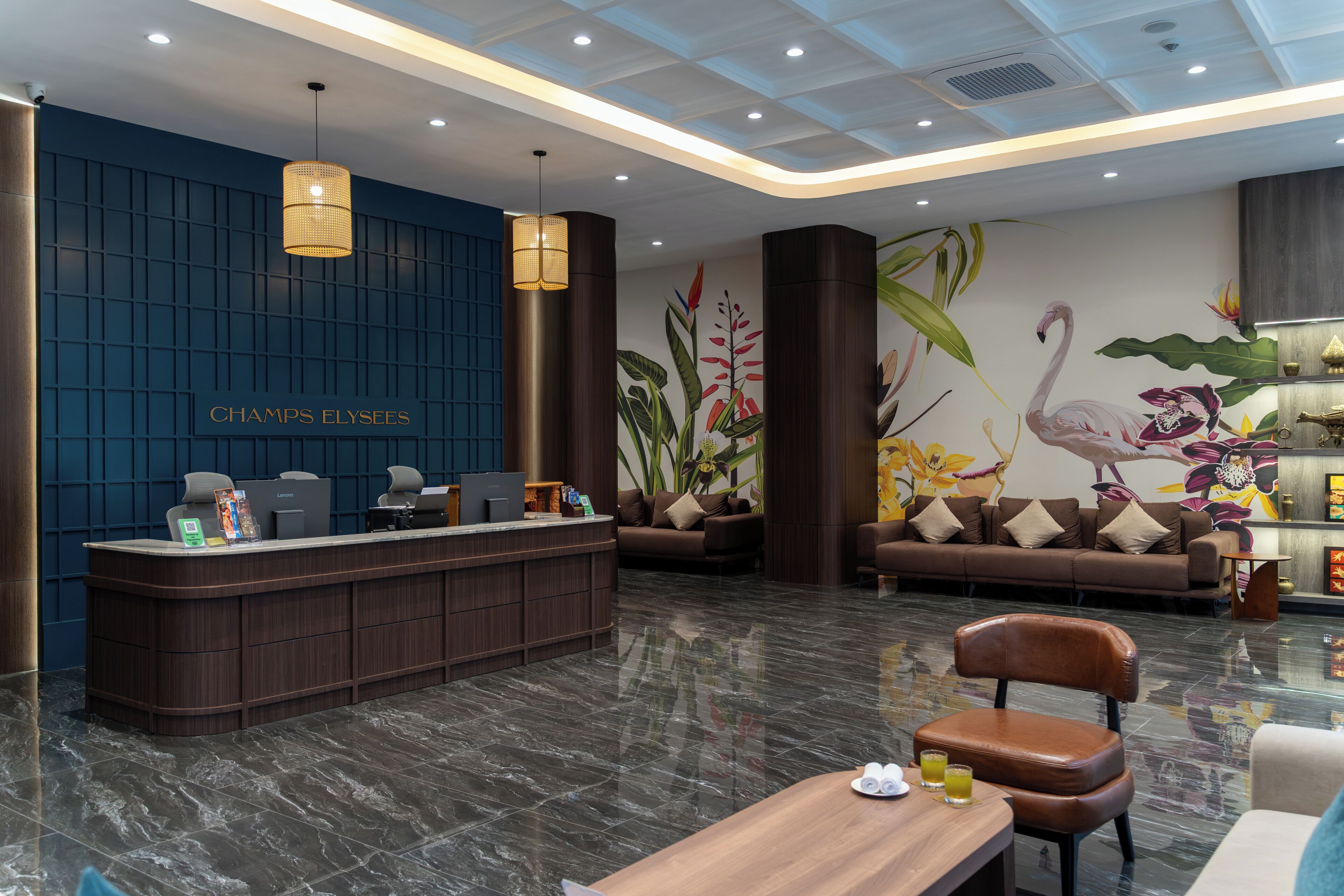 Un área de recepción moderna con pared azul, mostrador de recepción y zona de estar con sofás y una mesa de madera.
