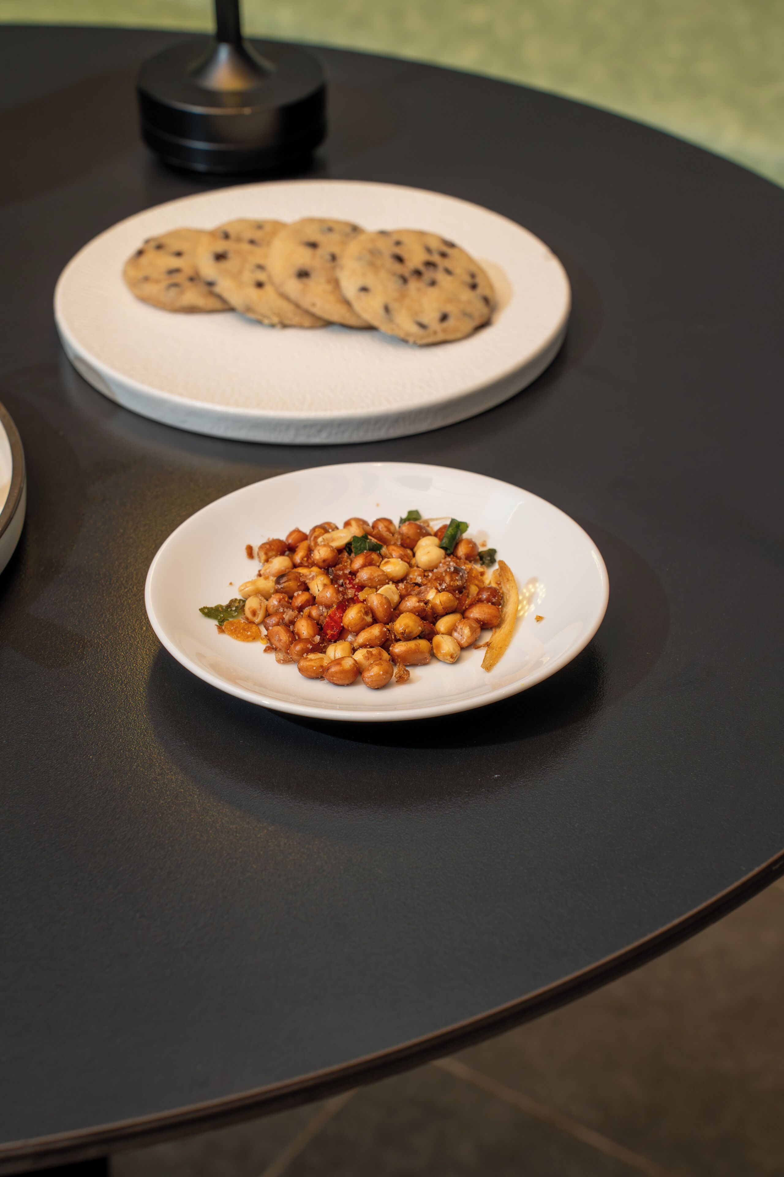 Deux assiettes blanches sur une table ronde, l’une contenant un plat et l’autre des biscuits.