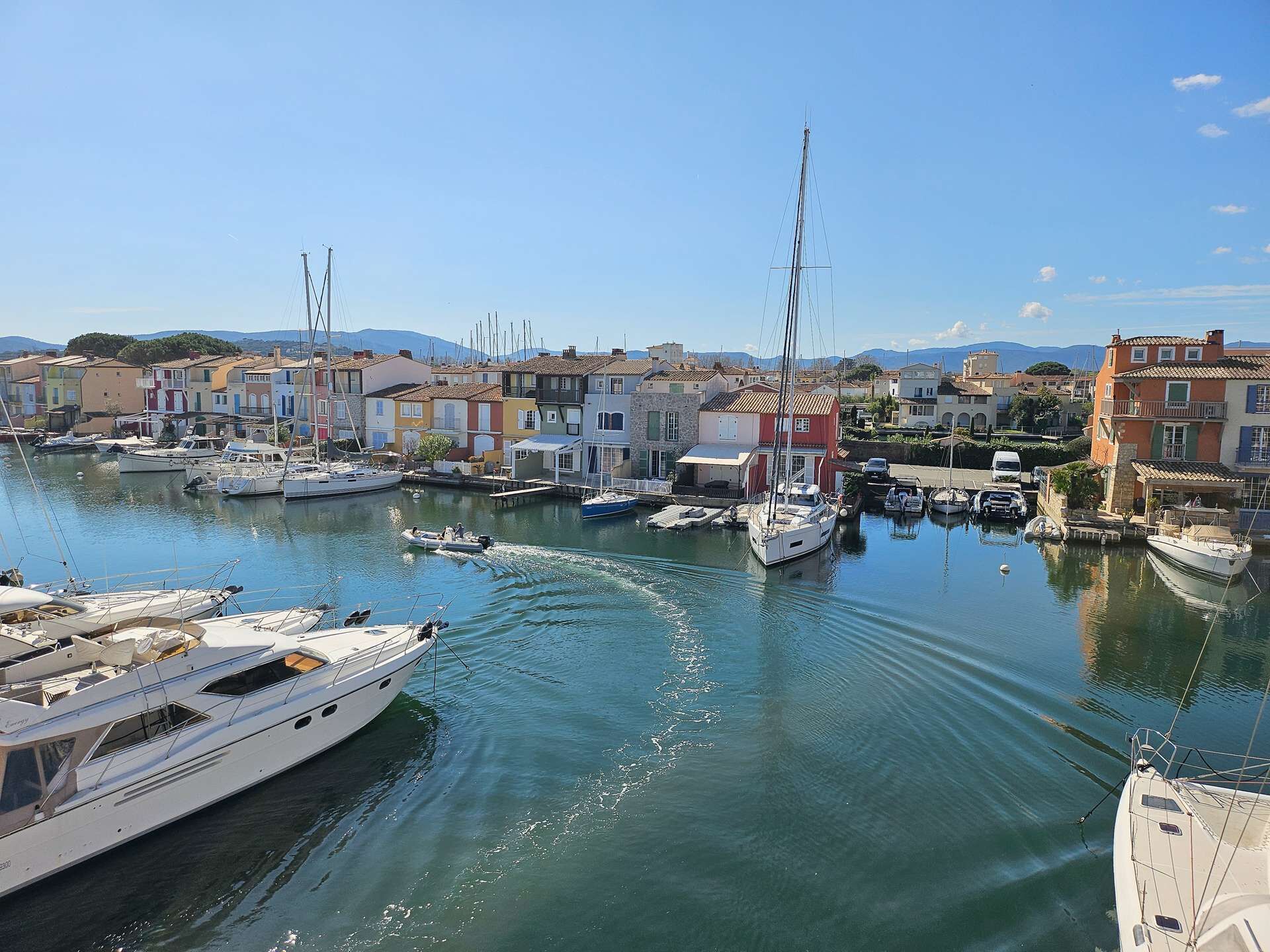 Un port de plaisance où sont amarrés des bateaux, entouré de bâtiments aux couleurs vives.