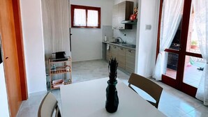Een compacte keuken met een eethoek, een raam met gordijnen en een tafeltje met een vaas.
