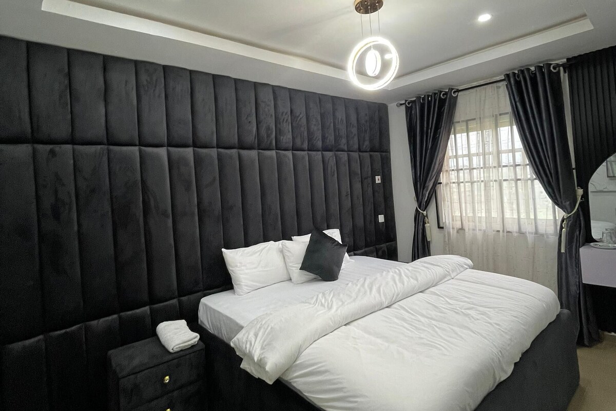 Une chambre moderne avec un grand lit, une table de chevet et un luminaire au plafond.