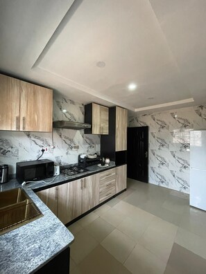 A modern kitchen with marble backsplash, wooden cabinets, and a built-in oven. - J3's Apartment & Lounge (Benin City)
