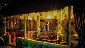 An outdoor seating area with tables and chairs, surrounded by greenery and decorative elements. - J3's Apartment & Lounge (Benin City)