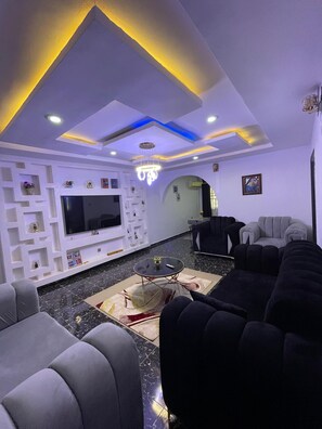 A modern living room with a flat-screen TV, comfortable seating, and decorative lighting. - J3's Apartment & Lounge (Benin City)