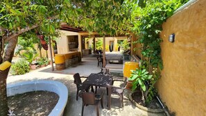 Eine Terrassenanlage im Freien mit Tisch, Stühlen, einem Grill und Kübelpflanzen.