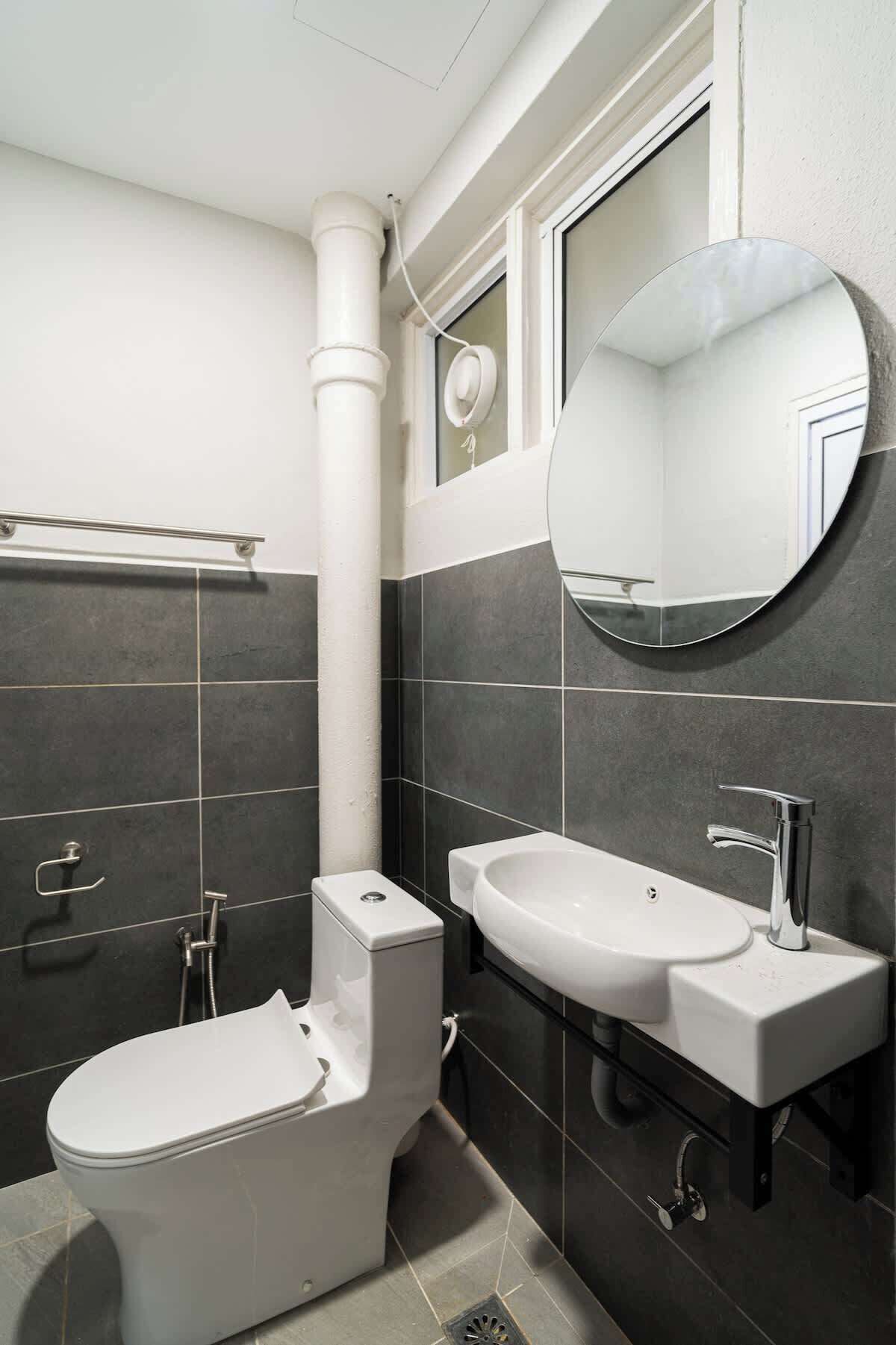 Et moderne badeværelse med toilet, håndvask og spejl.
