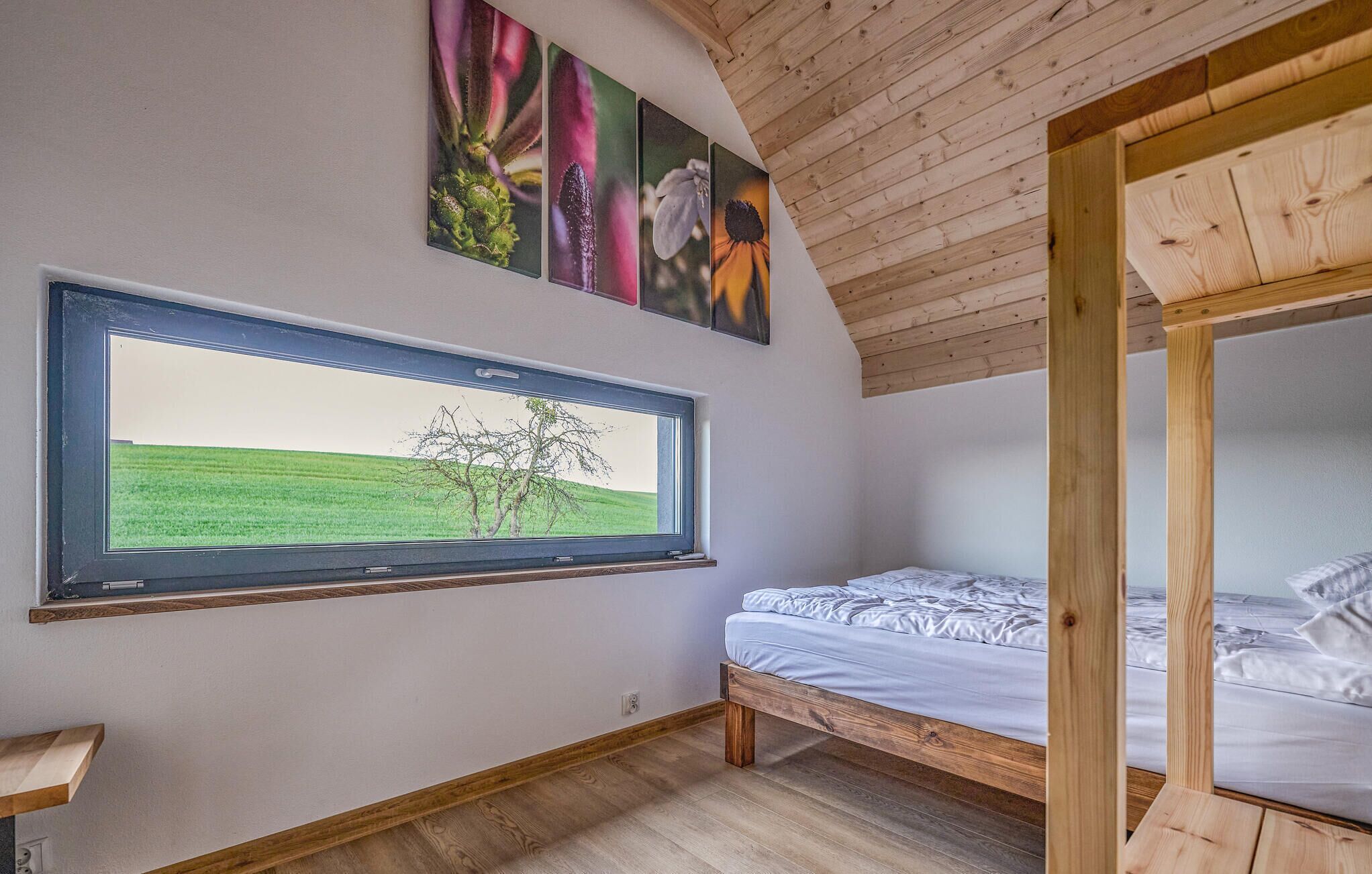 A bedroom with a window, wooden ceiling, and a bunk bed.