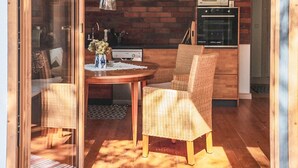 A cozy dining area with wicker chairs, a round wooden table, and a kitchen in the background.