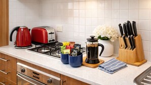 A kitchen with a red kettle, a toaster, a coffee maker, and a knife block on the counter.