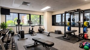 A gym with dumbbells, a bench, exercise bikes, and weightlifting equipment.