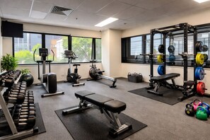 A gym with dumbbells, a bench, exercise bikes, and weightlifting equipment. - City Views • Steps to Melbourne Central & Trams (Melbourne)