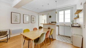 A modern kitchen with a wooden table and chairs, a refrigerator, and a window. - So Chic Montorgueil Paris (Paris)