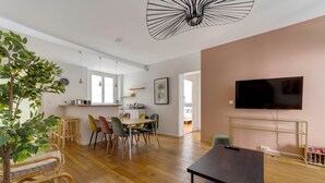 A modern living space with a dining area, a flat-screen TV mounted on the wall, and a large plant in the corner. - So Chic Montorgueil Paris (Paris)
