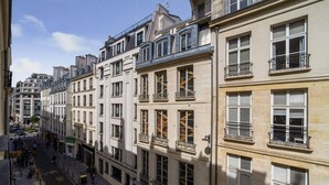 Een rij meerverdiepinggebouwen met balkons, een heldere lucht en een voetgangersstraat.