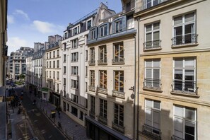 Eine Reihe mehrstöckiger Gebäude mit Balkonen, ein klarer Himmel und eine Fußgängerzone.