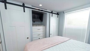 Un dormitorio con una cama, una puerta corredera para armario y una ventana con persianas.