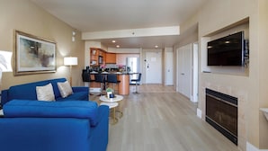 A modern living room with a blue sofa, a fireplace, and a kitchen in the background.