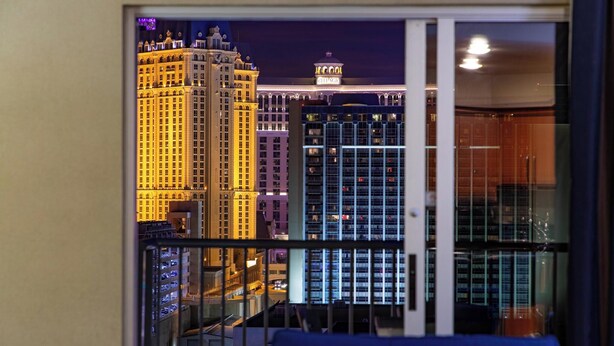 A view from a balcony with a cityscape at night, including illuminated buildings and a clear sky.