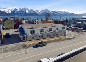 Un edificio con un mural de montaña, un estacionamiento y una carretera con vehículos.
