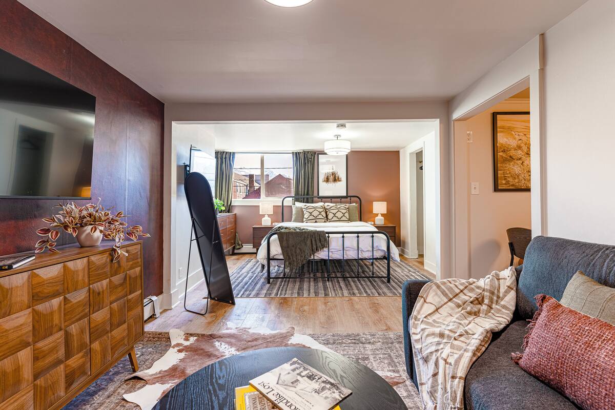 Ein Hotelzimmer mit Bett, Sofa, Fernseher, Kommode und Blick ins Freie.
