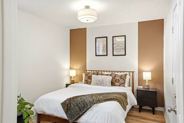 A bedroom with a bed, bedside tables, wall art, and a plant. - Hotel North (Seward)