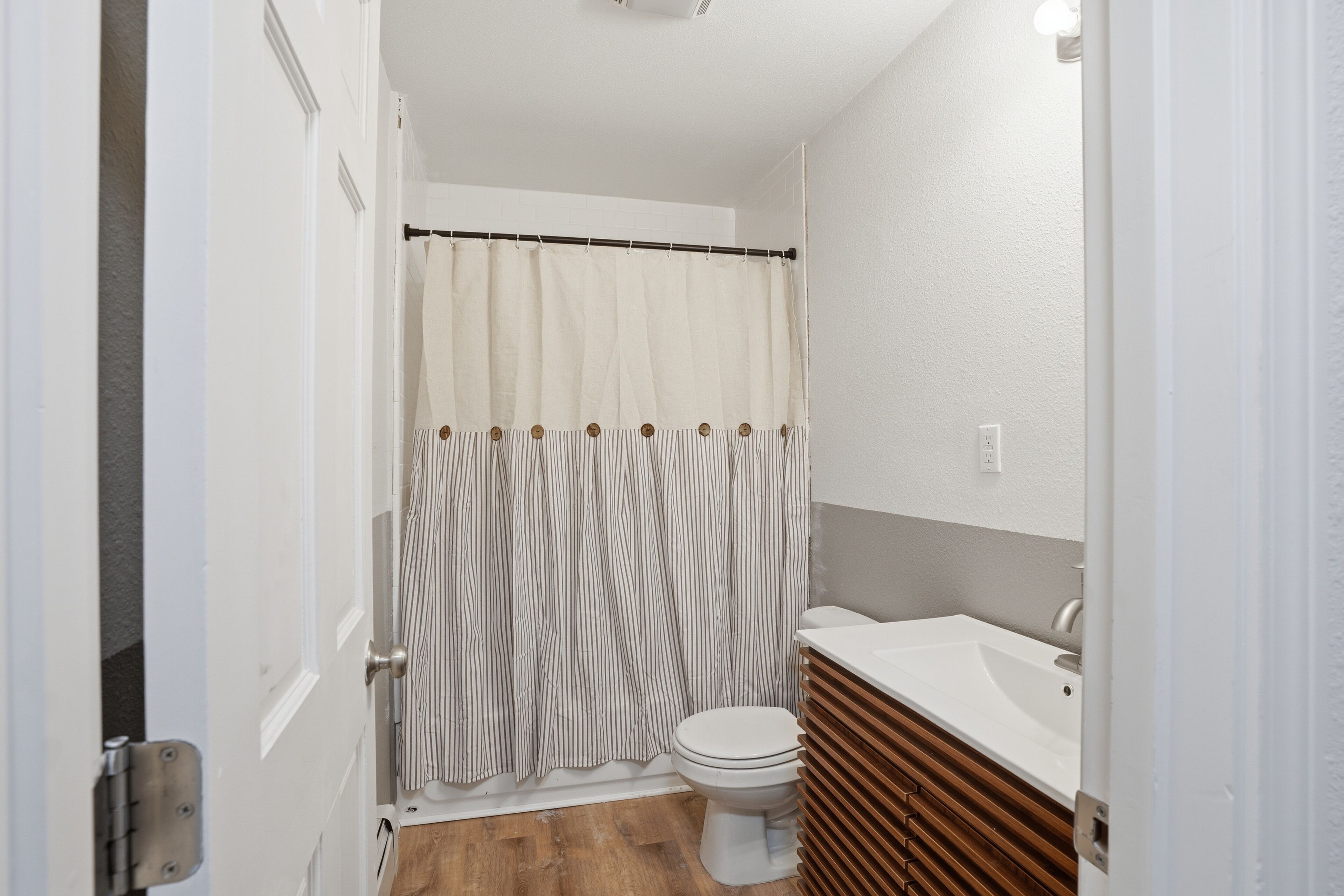Une salle de bain avec un rideau de douche, des toilettes et un lavabo.