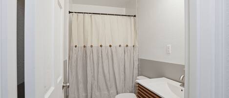 Une salle de bain avec un rideau de douche, des toilettes et un lavabo.