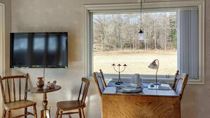 A room with a TV, wooden furniture, a table, and a window with a view of trees. - Amazing home in Slättåkra (Slättåkra)