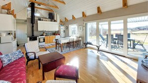 A spacious living area with a dining table, chairs, a sofa, and a kitchen with wooden beams. - Amazing home in Slättåkra (Slättåkra)