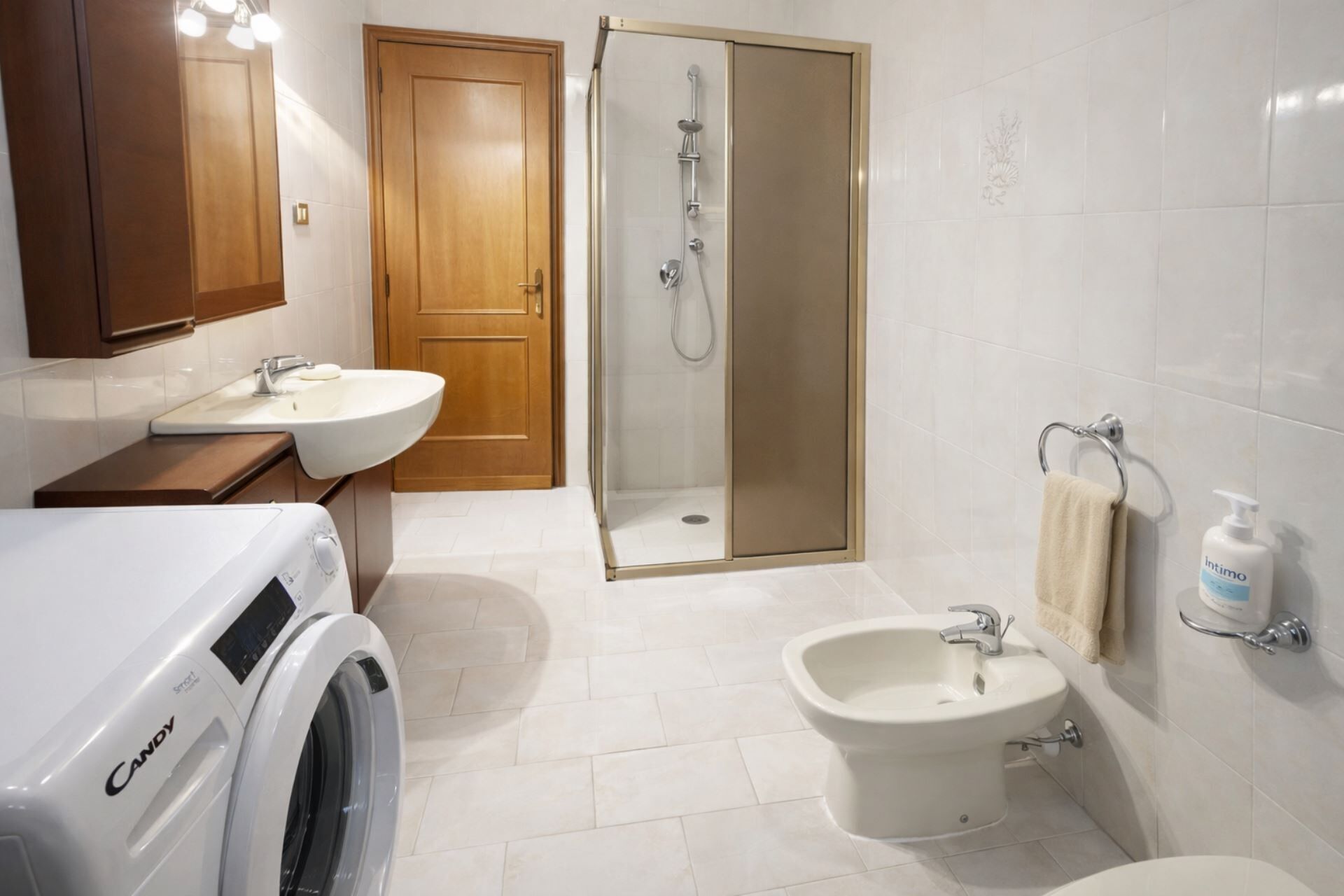 Un baño moderno con lavadora, bidé, ducha e inodoro.