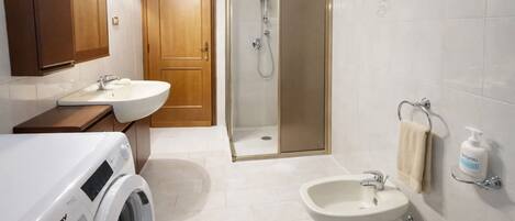 Un baño moderno con lavadora, bidé, ducha e inodoro.