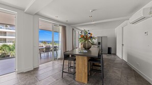 Una cocina moderna con una isla central, un área de comedor con sillas y un amplio ventanal con vistas al exterior.
