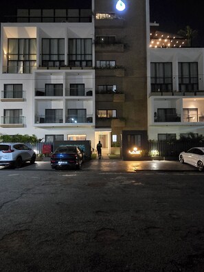 A multi-story building with balconies, a gated entrance, and parked cars. - Modern Studio in Accra near Airport & Mall (Accra)