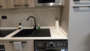 Una cocina compacta con microondas, lavavajillas y pileta.