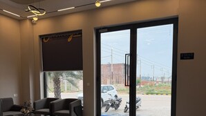 A modern interior with a seating area, a large glass door leading outside, and a ceiling with pendant lighting. - Hotel Eastleigh (Ludhiana)