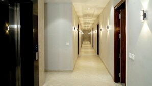 A corridor with doors, recessed lighting, and a tiled floor. - Hotel Eastleigh (Ludhiana)