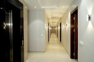 Un pasillo con puertas, iluminación empotrada y suelo de baldosas.